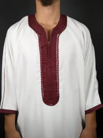 Mise en avant sur la broderie bordeaux au centre d’une gandoura blanche pour homme